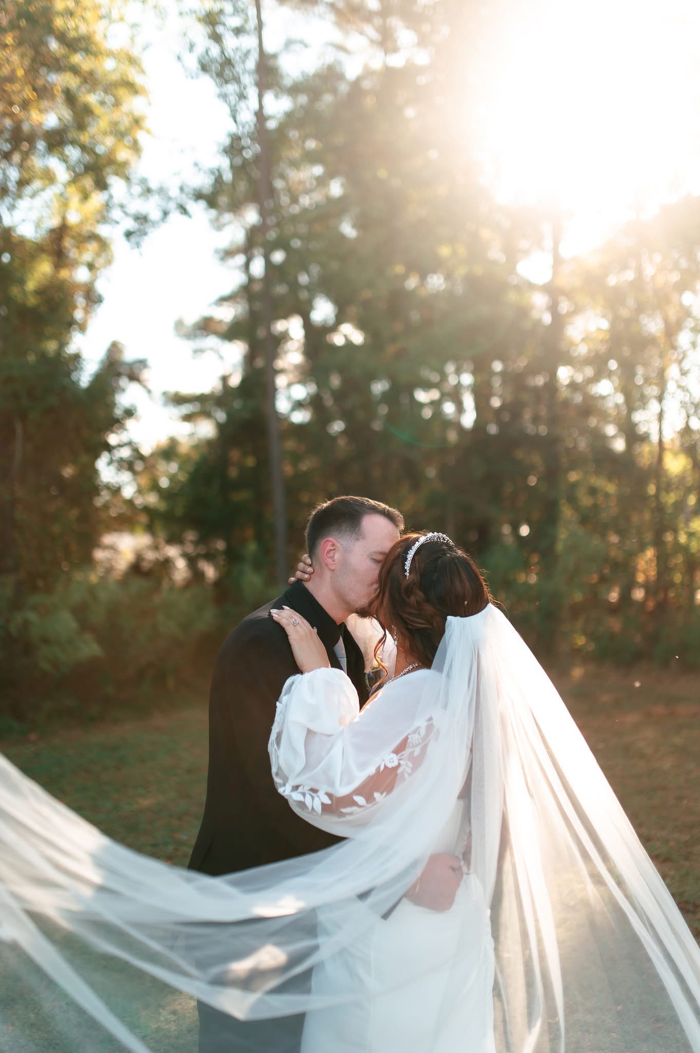 Bride and groom beneath the trees in soft golden light