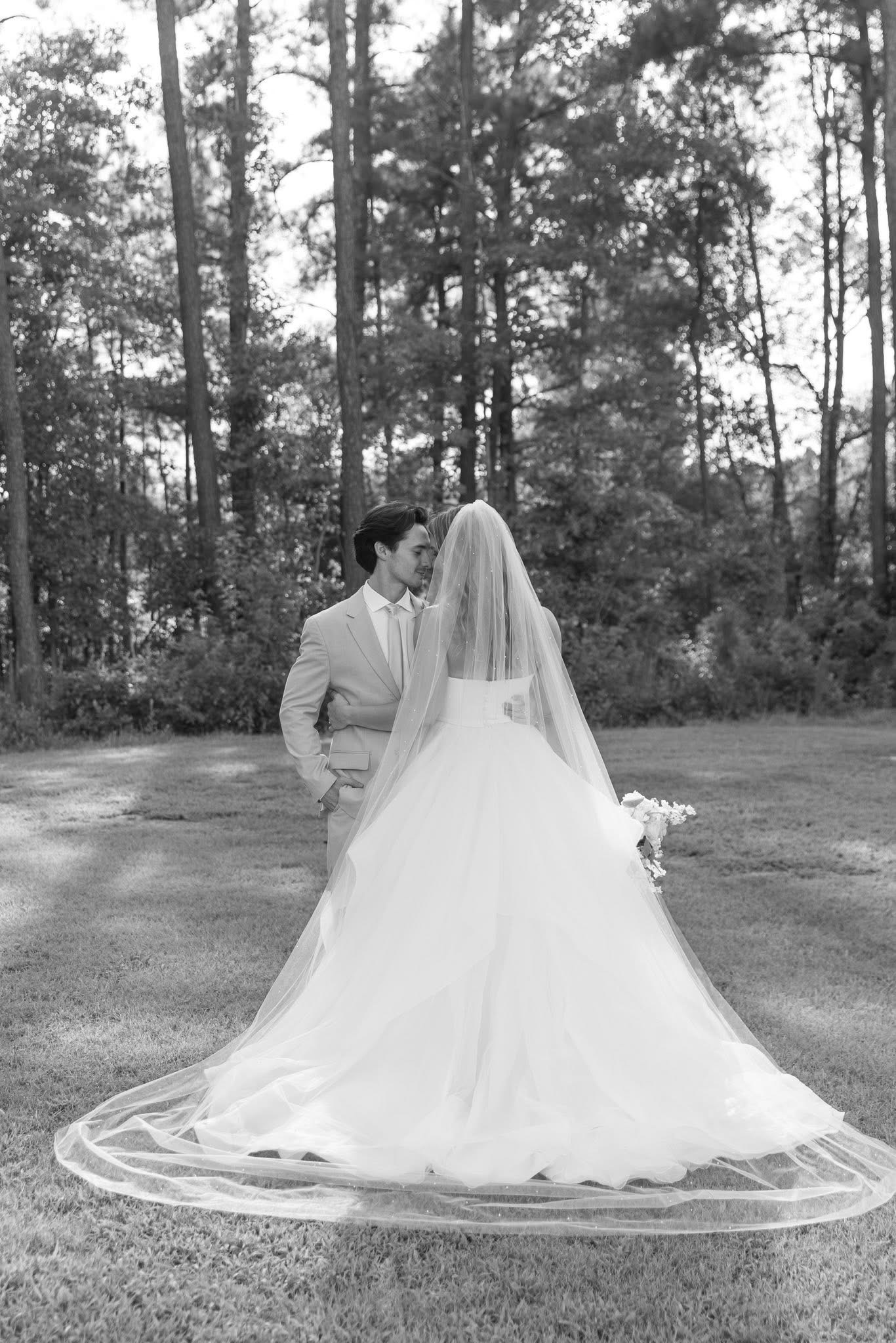 Black-and-white bridal portrait showing the gown and woodland setting