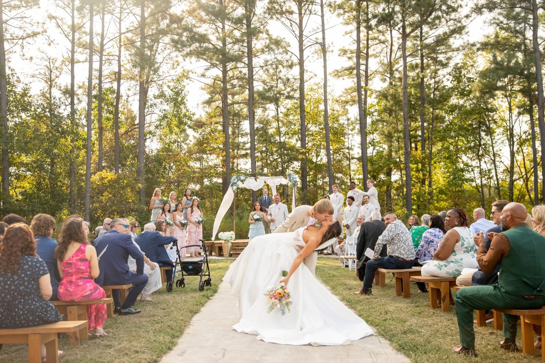 Newlyweds celebrating with a dip at the end of the woodland aisle