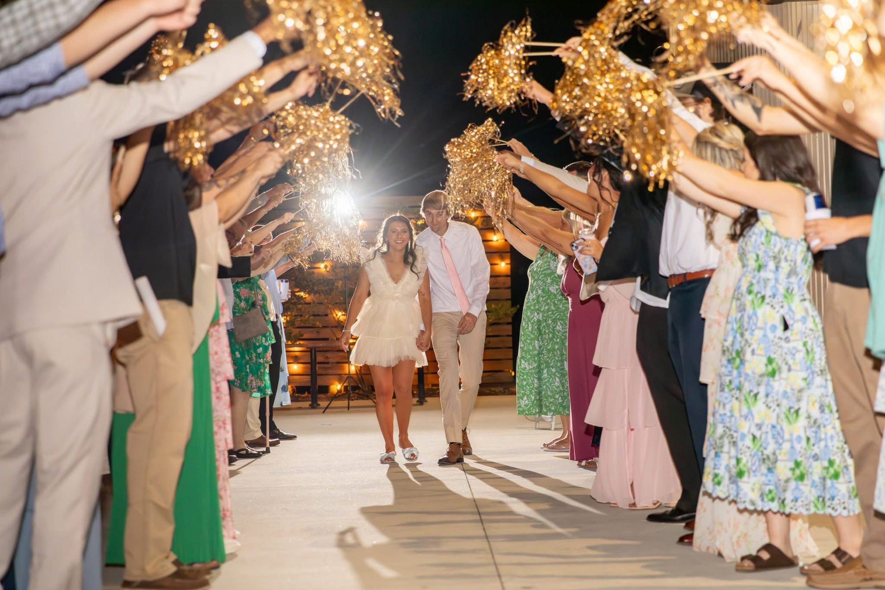 Guests holding sparklers as newlyweds make their evening exit